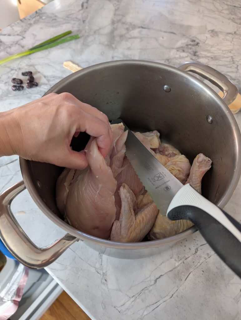 Step in making herbal chicken soup: Cut the chicken breast off to save for a later meal.