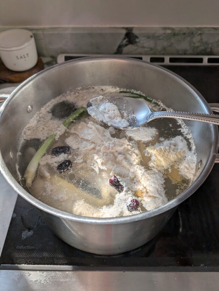 Prepared pot of healing chicken bone broth: skimming foam