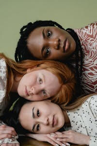 A portrait of three diverse women showcasing unity and friendship against a green background.