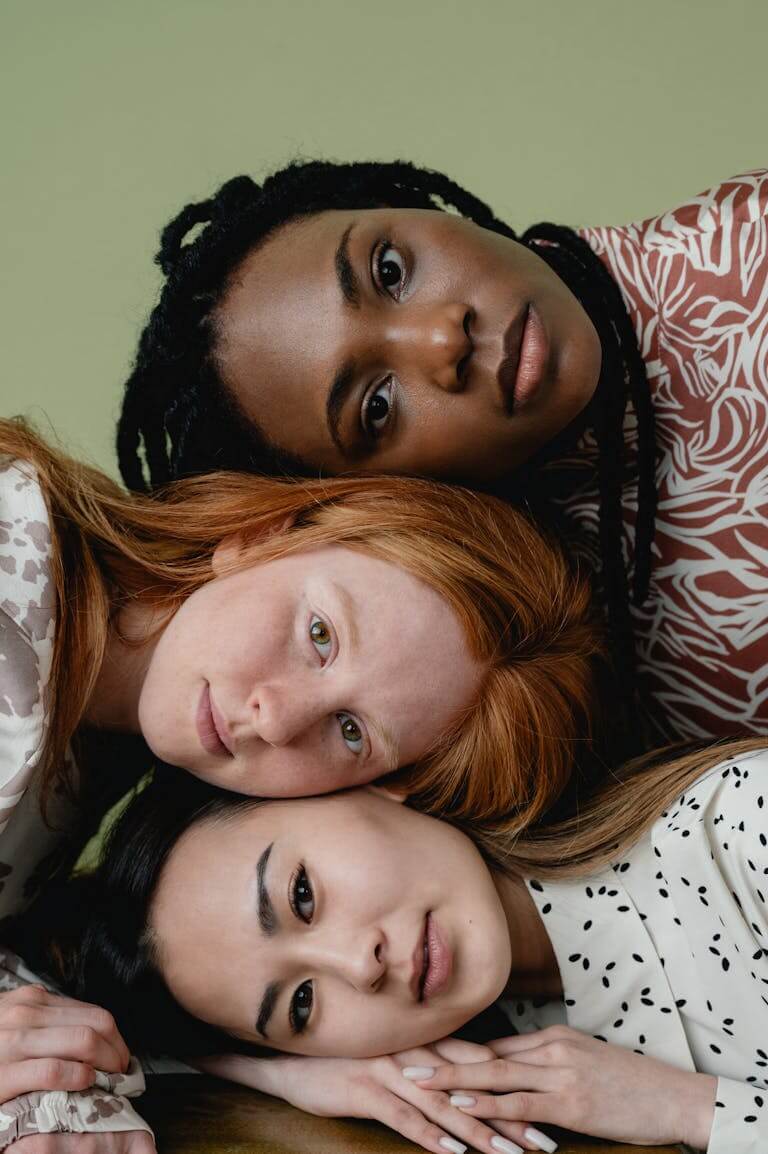 A portrait of three diverse women showcasing unity and friendship against a green background.