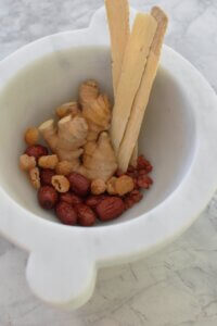 a bowl of astragalus, ginger, red dates, longan, and goji berries