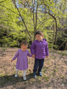 a young boy holding his little sister's hand
