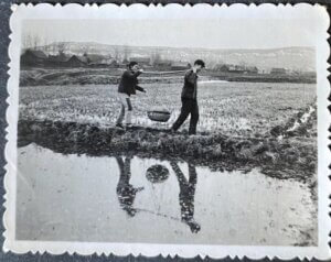 young woman and young man carrying a basket together next to a lake, antique photo in countryside of china