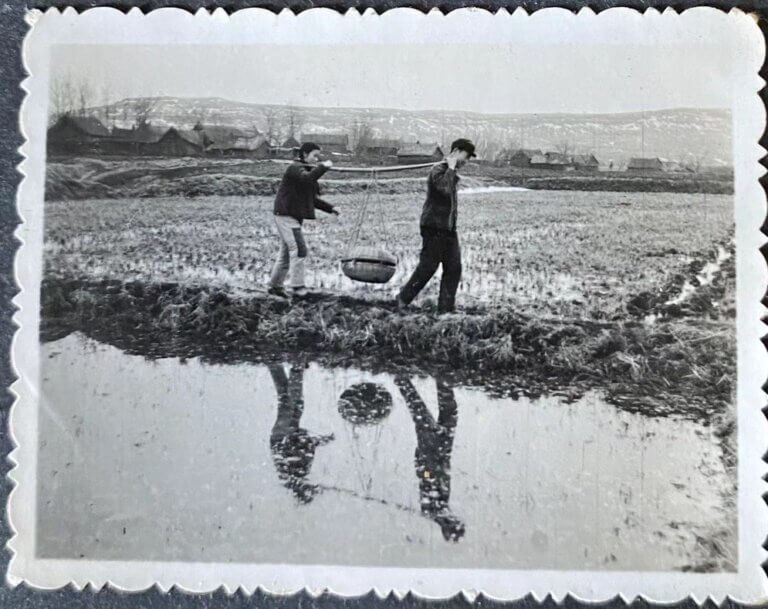 young woman and young man carrying a basket together next to a lake, antique photo in countryside of china