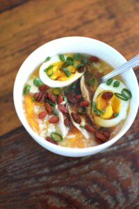 chicken and sweet potato congee in a bowl with egg scallion and goji berries